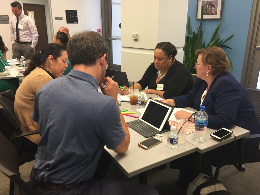 four professionals with tablets sitting around an office table in conversation